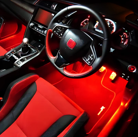 Sports car interior with red LED accent lighting. Add-On® Anywhere Lights provide a sharp, racing-inspired red glow on pedals and floors for a high-performance look.