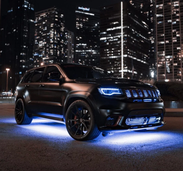 White LED car underglow lighting kit for a neon ground effect. Durable Anywhere Lights by Add-On® installed on a black SUV for a stunning city night appearance.